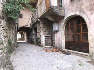 un callejón con un edificio con una puerta de madera en Maison de village au cœur des remparts, en Sainte-Eulalie-du-Cernon