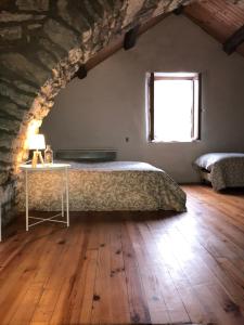 1 dormitorio con cama, mesa y ventana en Maison de village au cœur des remparts, en Sainte-Eulalie-du-Cernon