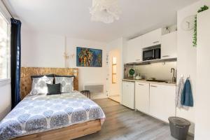 a bedroom with a bed and a kitchen with white cabinets at Studios avec parking, clim, balcon, proche tram in Grenoble