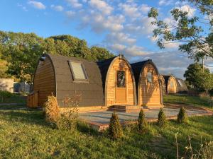 a wooden cabin in the middle of a field at Rabbit Glamping Pod School House Farm in Leighton