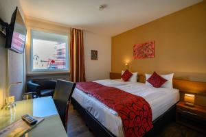 ein Hotelzimmer mit einem Bett, einem Schreibtisch und einem Fenster in der Unterkunft Otto's Parkhotel Saarlouis in Saarlouis