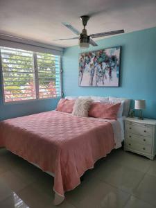 Schlafzimmer mit einem rosa Bett und einem Deckenventilator in der Unterkunft Relaxing Property with Stunning Views and Pool in Toa Baja
