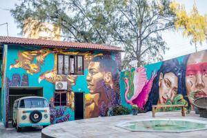 Salve Maloca Hostel في فورتاليزا: لوحة جدارية على جانب مبنى مع سيارة متوقفة في الأمام