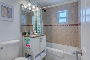 a bathroom with a toilet and a sink and a tub at Bathing Suit Beach Bungalow in Ormond Beach +23 photos