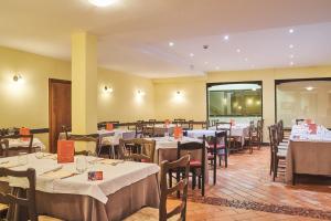 un ristorante con tavoli e sedie con tovaglie bianche di Hotel Dolomiti a Brentonico