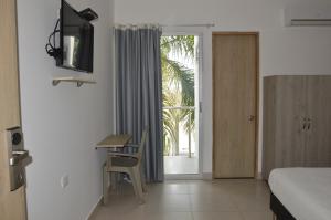 Schlafzimmer mit einem Bett, einem Schreibtisch und einem Fenster in der Unterkunft Hotel Ranchería Campestre in Sahagún