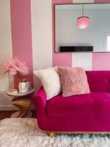 a purple couch in a pink room with a mirror at Dolly's Delight - Boutique Bliss Mins From Broadway in Nashville