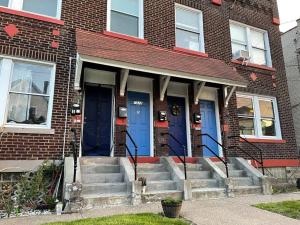 a brick building with blue doors and stairs in front at Lovely 2BR w Office space - KING BED & ALEXA in Pittsburgh