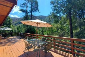 a table and chairs on a deck with an umbrella at Redwood Retreat, Mountains, Adventure and Nature in Ponderosa