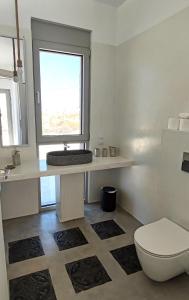 a bathroom with a toilet and a sink and a window at Komos Beach Estate in Kalamaki Heraklion