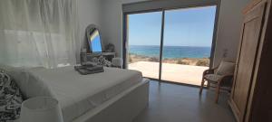 a bedroom with a bed and a view of the ocean at Komos Beach Estate in Kalamaki