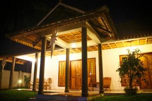 a white house with a porch at night at Green Court Cottages in Thekkady