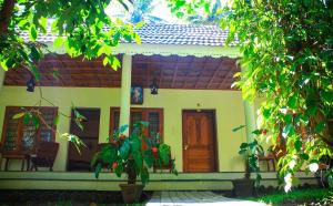 a small yellow house with a porch at Green Court Cottages in Thekkady
