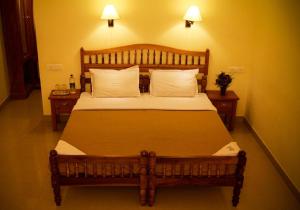 1 dormitorio con 1 cama grande de madera y 2 mesas en Green Court Cottages, en Thekkady