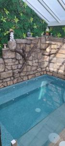 a swimming pool with a stone wall next to at El MANANTIAL in Zahara de la Sierra