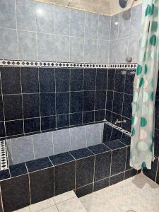 y baño con ducha y paredes de azulejos negros y grises. en LÍZU Tu casa en un pueblo zapoteca, en Teotitlán del Valle