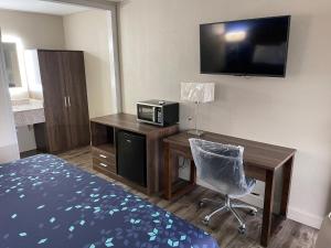 Habitación de hotel con escritorio, cama y TV en Scottish Inns - Commerce, en Commerce