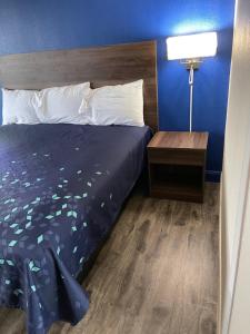 Cama en habitación de hotel con pared azul en Scottish Inns - Commerce, en Commerce