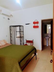 a bedroom with a green bed and a sink at Hostal Los Faroles Chicoana in Chicoana