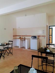 una habitación con mesas y sillas y una cocina en Hostal Los Faroles Chicoana en Chicoana