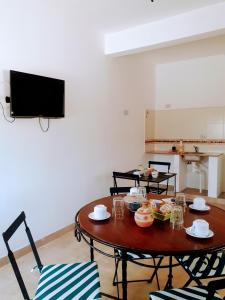 a living room with a table and chairs and a tv at Hostal Los Faroles Chicoana in Chicoana