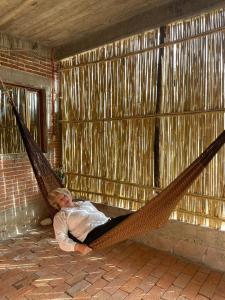 a man laying in a hammock in a room at LÍZU Tu casa en un pueblo zapoteca in Teotitlán del Valle