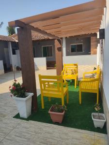 a group of yellow benches sitting under a pergola at Studios Unamar in Cabo Frio