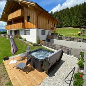 una bañera de hidromasaje en un patio junto a una casa en Appartement Förra, en Valle di Casies