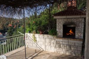 a stone fireplace on a patio with a deck at Apartments Marijana in Zavalatica