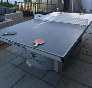 una mesa de ping pong con una paleta de ping pong en Drystone Manor - Swim Hot Tub, Tennis, Gatherings en Iron Acton