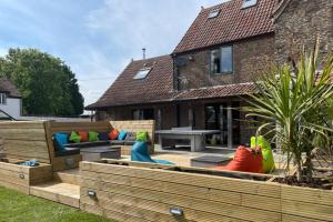 un patio trasero con muebles de madera y una casa en Drystone Manor - Swim Hot Tub, Tennis, Gatherings en Iron Acton