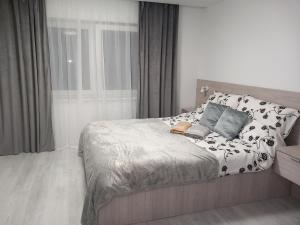 ein Schlafzimmer mit einem Bett mit einer schwarz-weißen Bettdecke in der Unterkunft Angel in Kołobrzeg