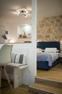 een slaapkamer met een blauw bed en een stenen muur bij Torkul in Šibenik