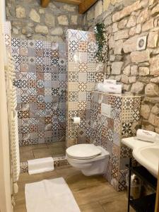 a bathroom with a toilet and a stone wall at Zsóka Fogadója in Szentantalfa