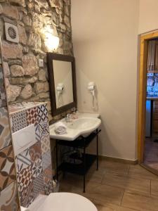 a bathroom with a sink and a stone wall at Zsóka Fogadója in Szentantalfa