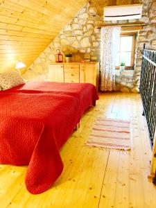 a bedroom with a red bed and a stone wall at Zsóka Fogadója in Szentantalfa