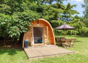 a small wooden cabin with a table and an umbrella at Apple Mount Retreat in Lavenham