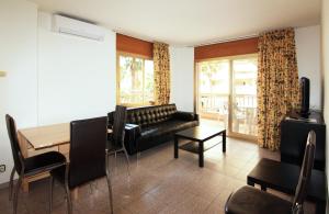 a living room with a black leather couch and a table at Apartamentos Indasol in Salou