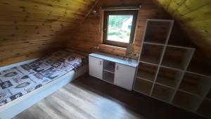 1 dormitorio en una cabaña de madera con cama y ventana en Domek nad jeziorem, en Gowidlino
