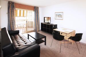 Apartamentos Indasol في سالو: غرفة معيشة مع أريكة وطاولة مع كراسي