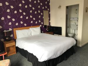 ein Schlafzimmer mit einem großen weißen Bett mit einer lila Wand in der Unterkunft The Old Coach House in Buckie