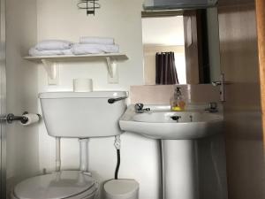 a white bathroom with a toilet and a sink at The Old Coach House in Buckie