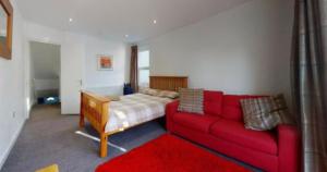 a living room with a red couch and a bed at Myrtle Villa Rooms in Weymouth