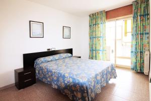 a bedroom with a bed and a window with curtains at Apartamentos Indasol in Salou