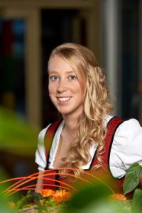 Uma jovem mulher com cabelo loiro comprido, de colete. em Hotel Wieser em Mittersill