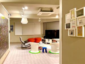 a living room with white chairs and a tv at Sohostel Korea in Busan