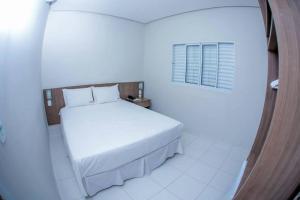 a bedroom with a white bed and a window at Hotel Império in Paranaíba
