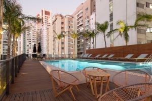un balcón con piscina, sillas y edificios en 360 Suítes Facto Paulista - Apartamentos mobiliados, en São Paulo