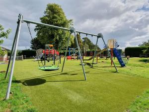 a park with a playground with slides and swings at Maen Llwyd in Llanyre