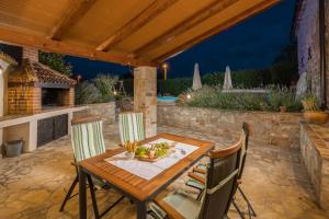 a wooden table and chairs on a patio at night at Villa Nonni-romantic stone house in Višnjan
